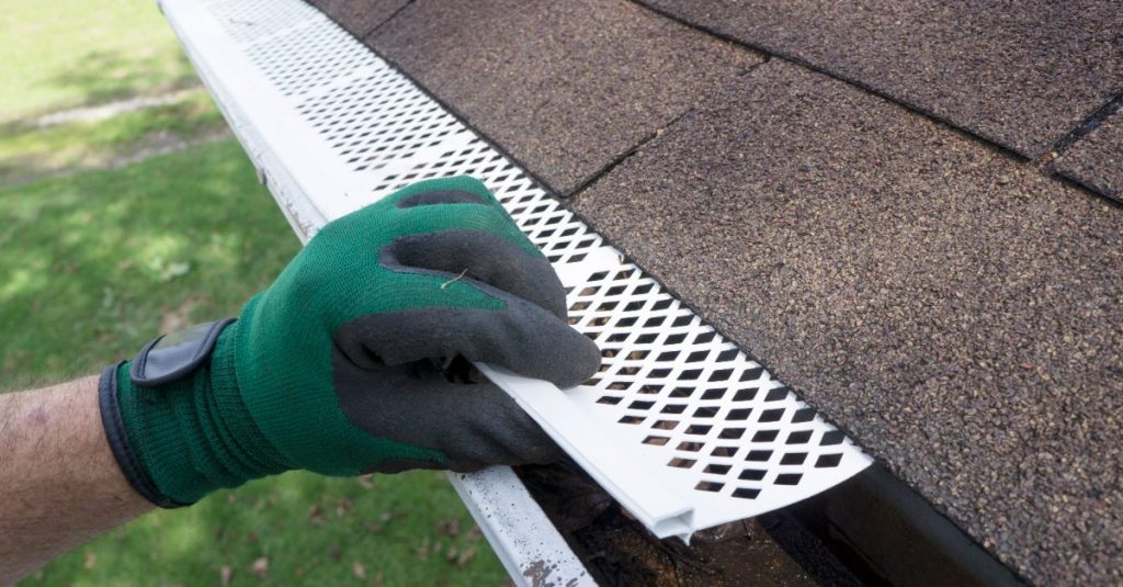 A technician installing gutter guards on a home’s gutters after successfully completing gutter replacement in Kansas City.